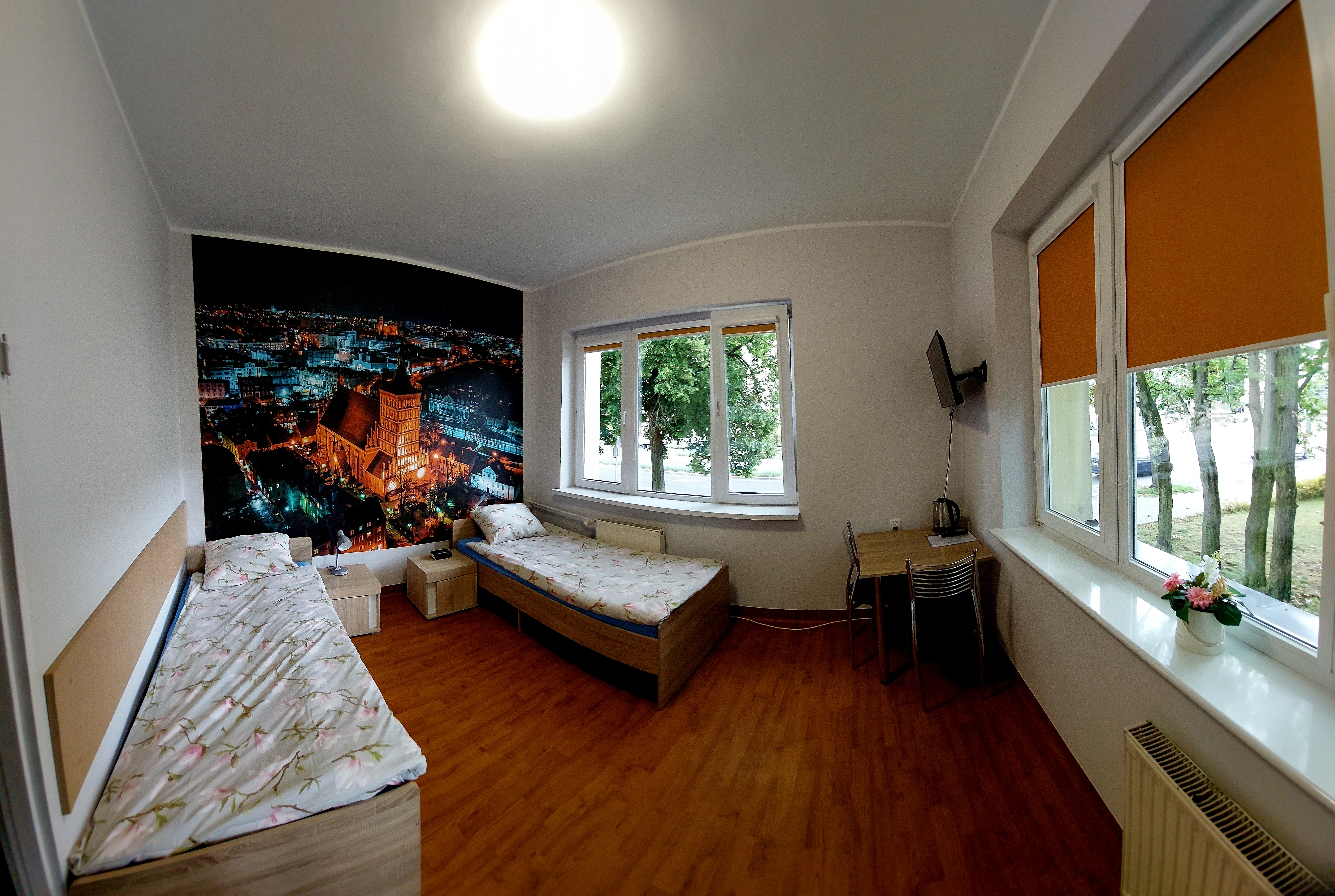 A double room with a bathroom in the facility No. 1 Kosciuszko. In the background on the wall wallpaper showing Olsztyn from a bird's eye view.  